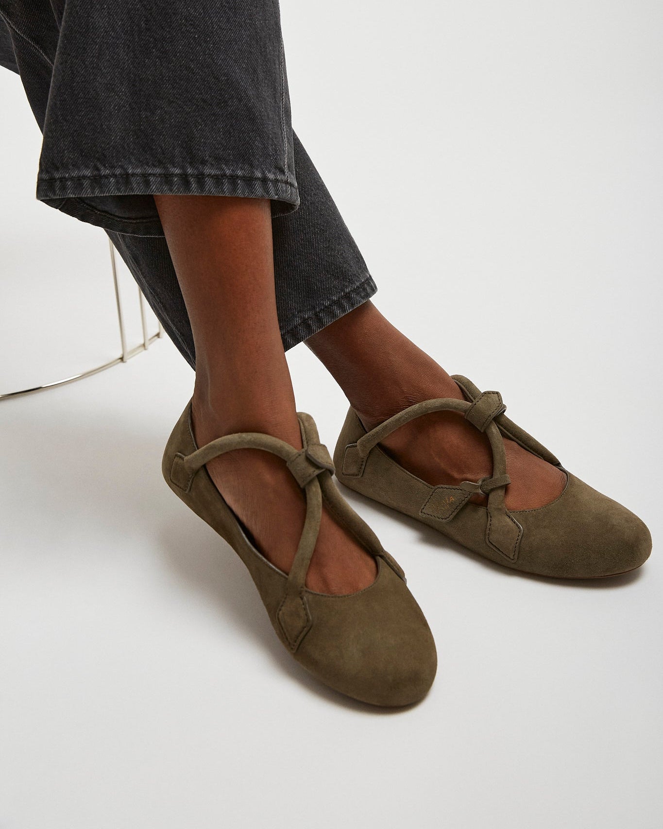 Brown ballet flats worn with dark jeans on a white background