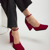 Red high-heeled shoes worn with black pants on a white background