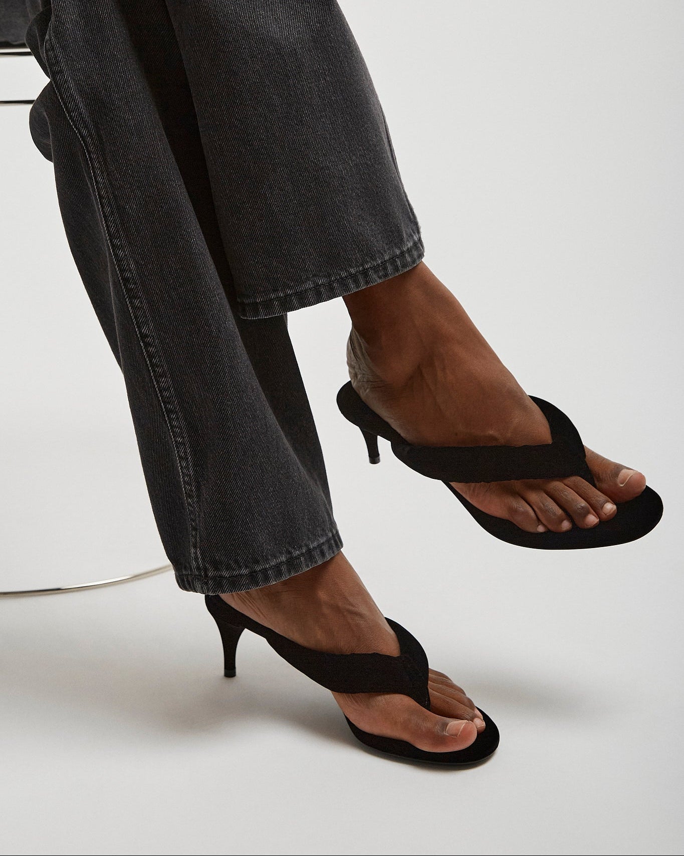 Person wearing black high-heeled sandals with a white background