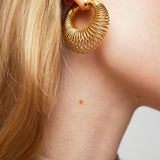 Gold hoop earring worn by a person with a neutral background