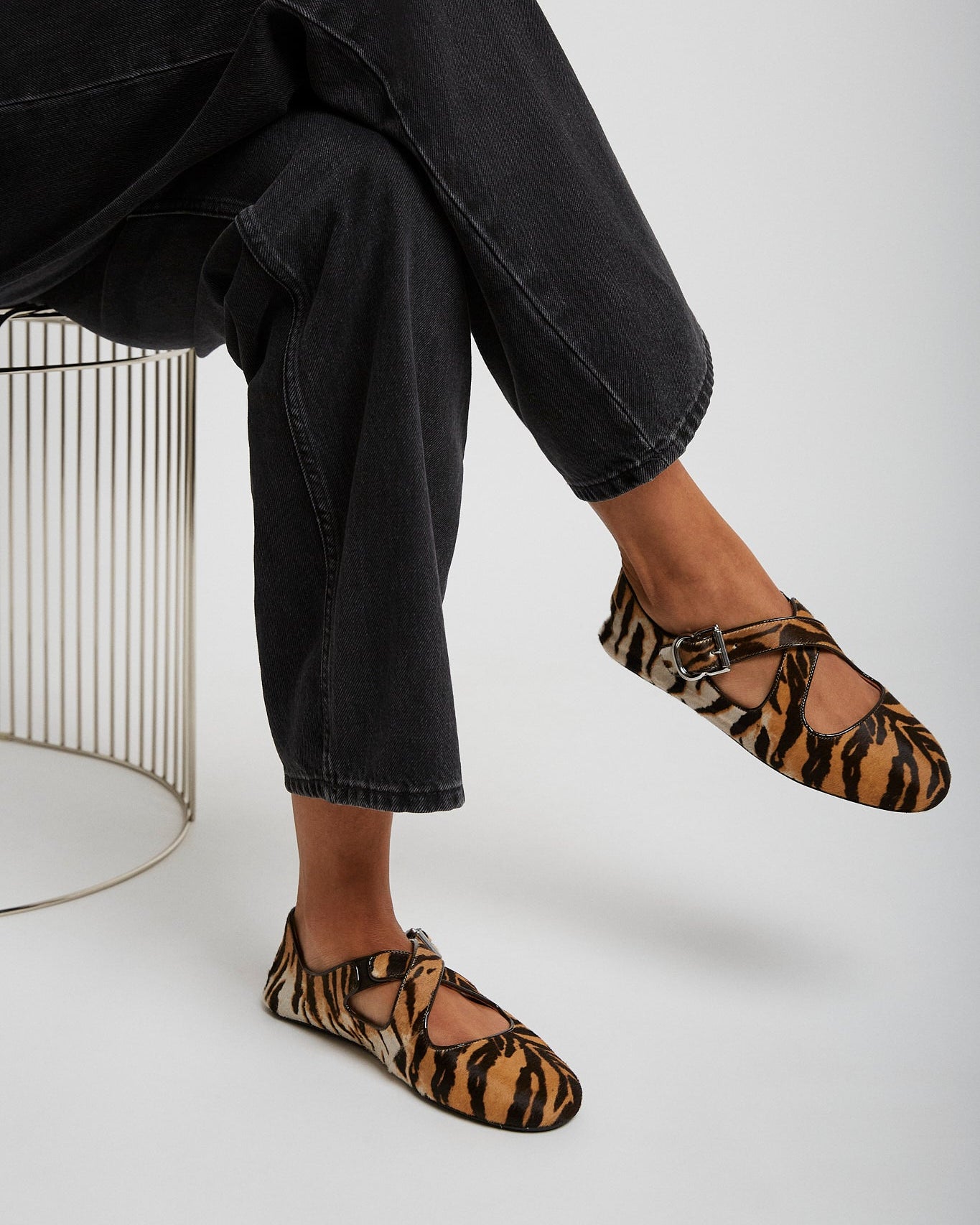 Person wearing leopard print flats and black jeans on a white background