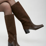 Brown knee-high boots worn with tights on a white background