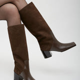 Brown knee-high boots worn with tights on a white background