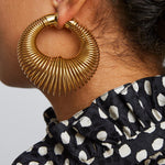 Close-up of a person wearing a gold hoop earring with a blurred background