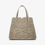 Beige handbag with decorative studs on a white background