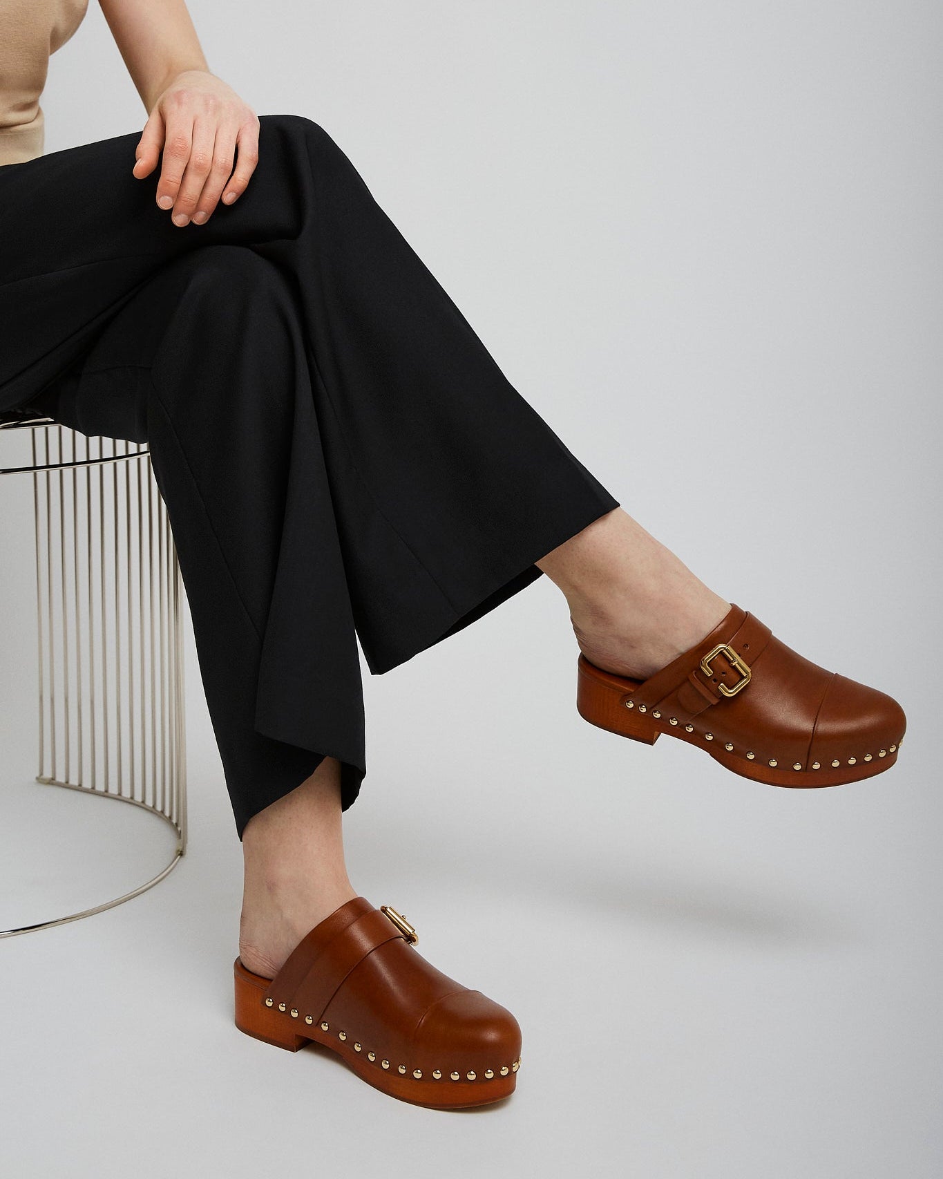 Person wearing brown clogs with a neutral background