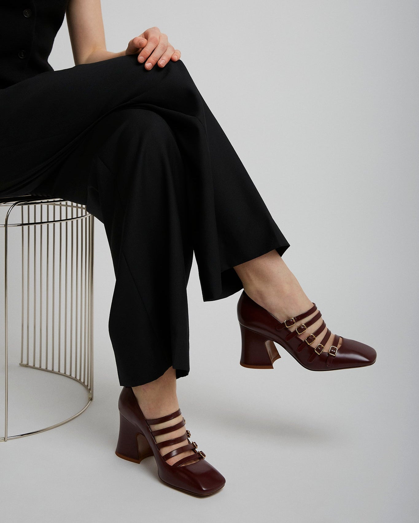 Person wearing a black outfit with brown shoes on a white background