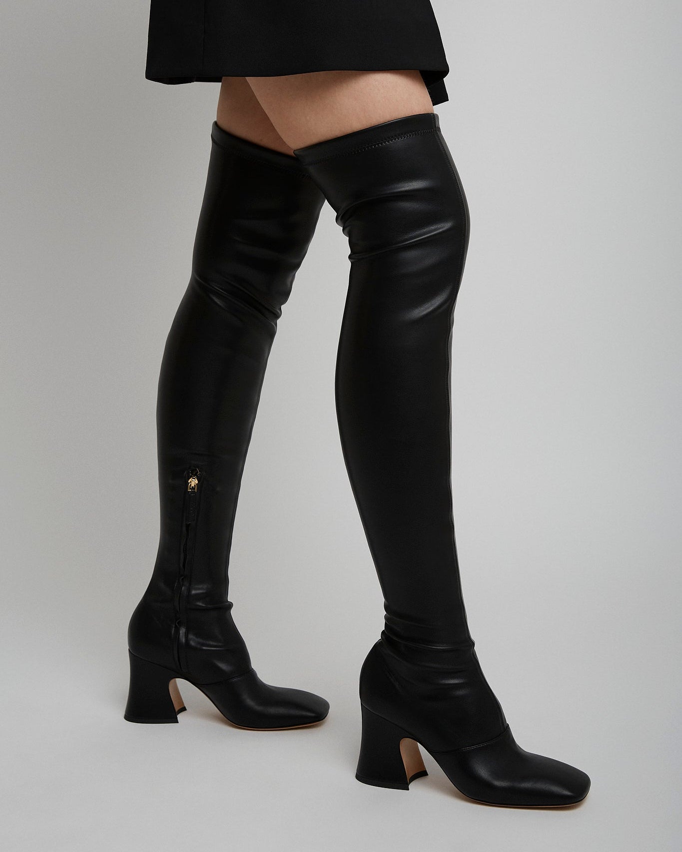 Black leather knee-high boots on a plain background