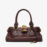 Brown leather handbag with gold accents on a white background