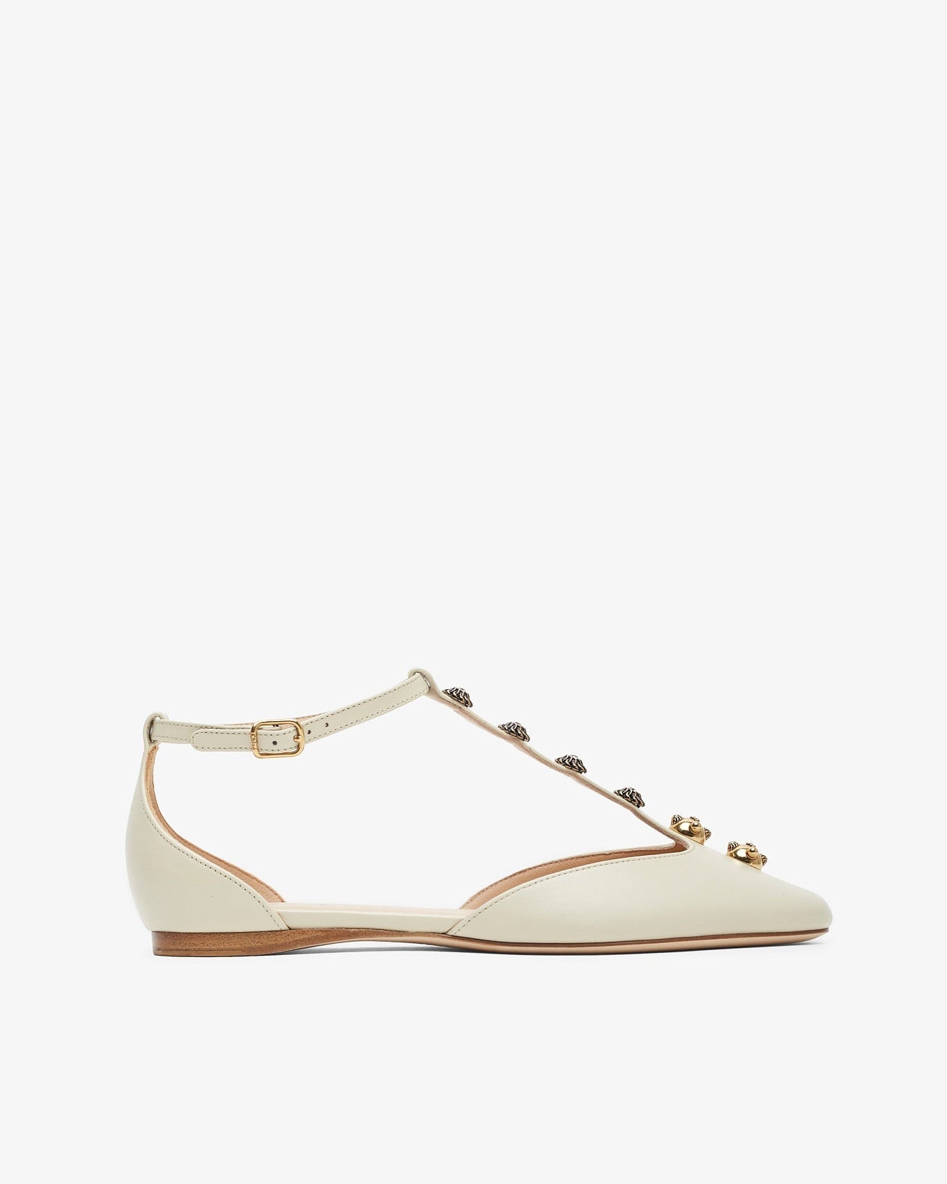 White flat shoe with decorative straps on a white background