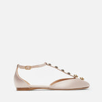 Beige flat shoe with decorative straps on a white background