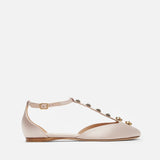 Beige flat shoe with decorative straps on a white background
