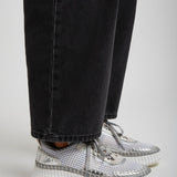 Silver high-top sneakers worn with black jeans on a light gray background