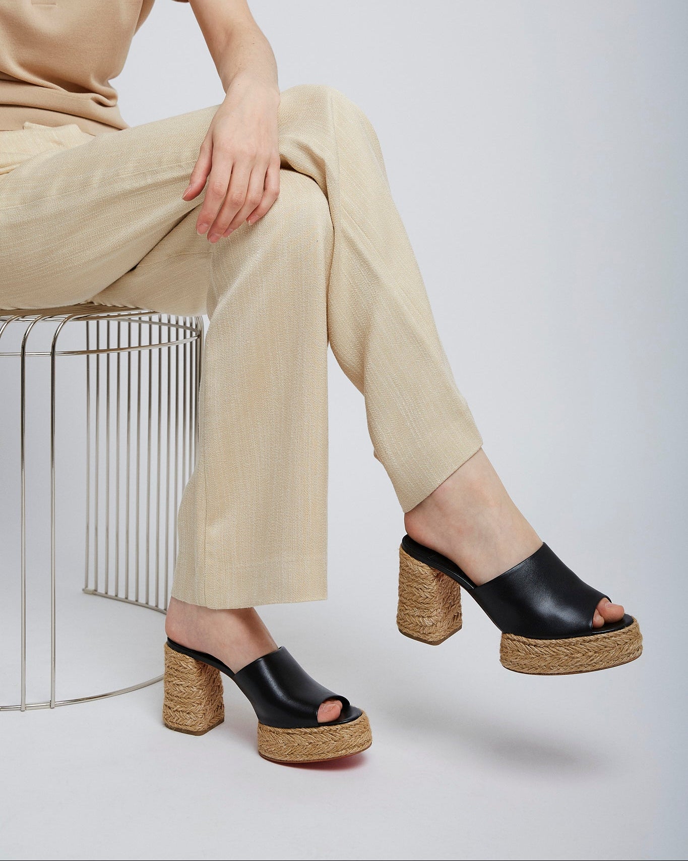 Person wearing black platform sandals with cork soles on a white background