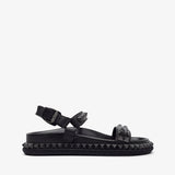 Black sandal with studded details on a white background