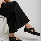 Person wearing black sandals and wide-leg pants sitting on a white background