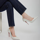Person wearing dark jeans and white high-heeled shoes with red soles on a light gray background