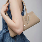 Person holding a beige handbag with a gray background