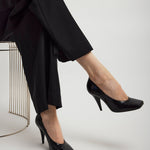 Person wearing black high-heeled shoes and pants on a white background