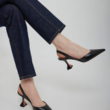 Person wearing black high-heeled shoes and blue jeans on a plain background