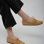 Tan shoes worn with black pants on a plain background