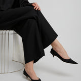 Person wearing a black outfit with wide-leg pants and black shoes on a white background