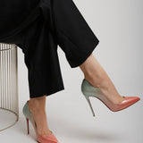 Person wearing black pants and pink high-heeled shoes on a white background