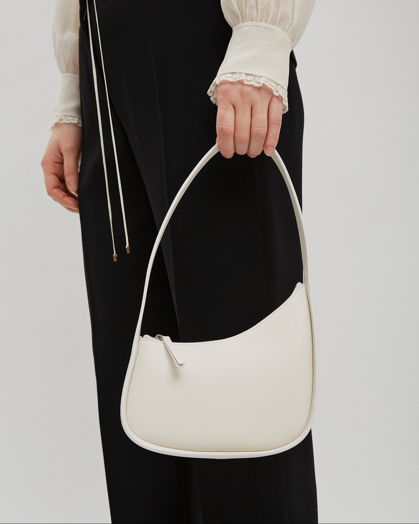 Person holding a white handbag against a plain background